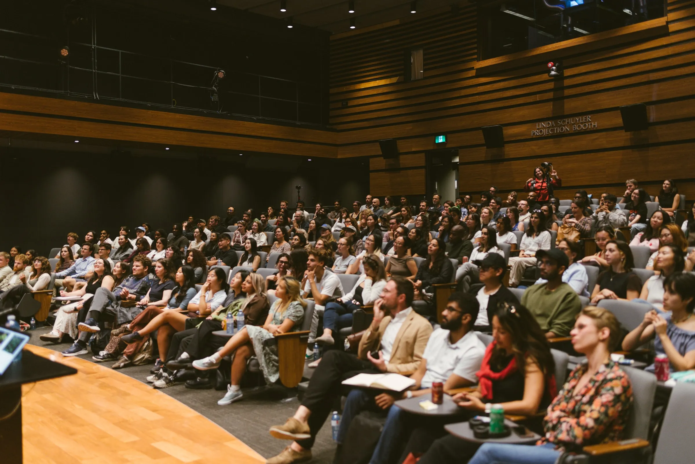 A wide view of the full, attentive audience in the tiered Innis Town Hall auditorium.