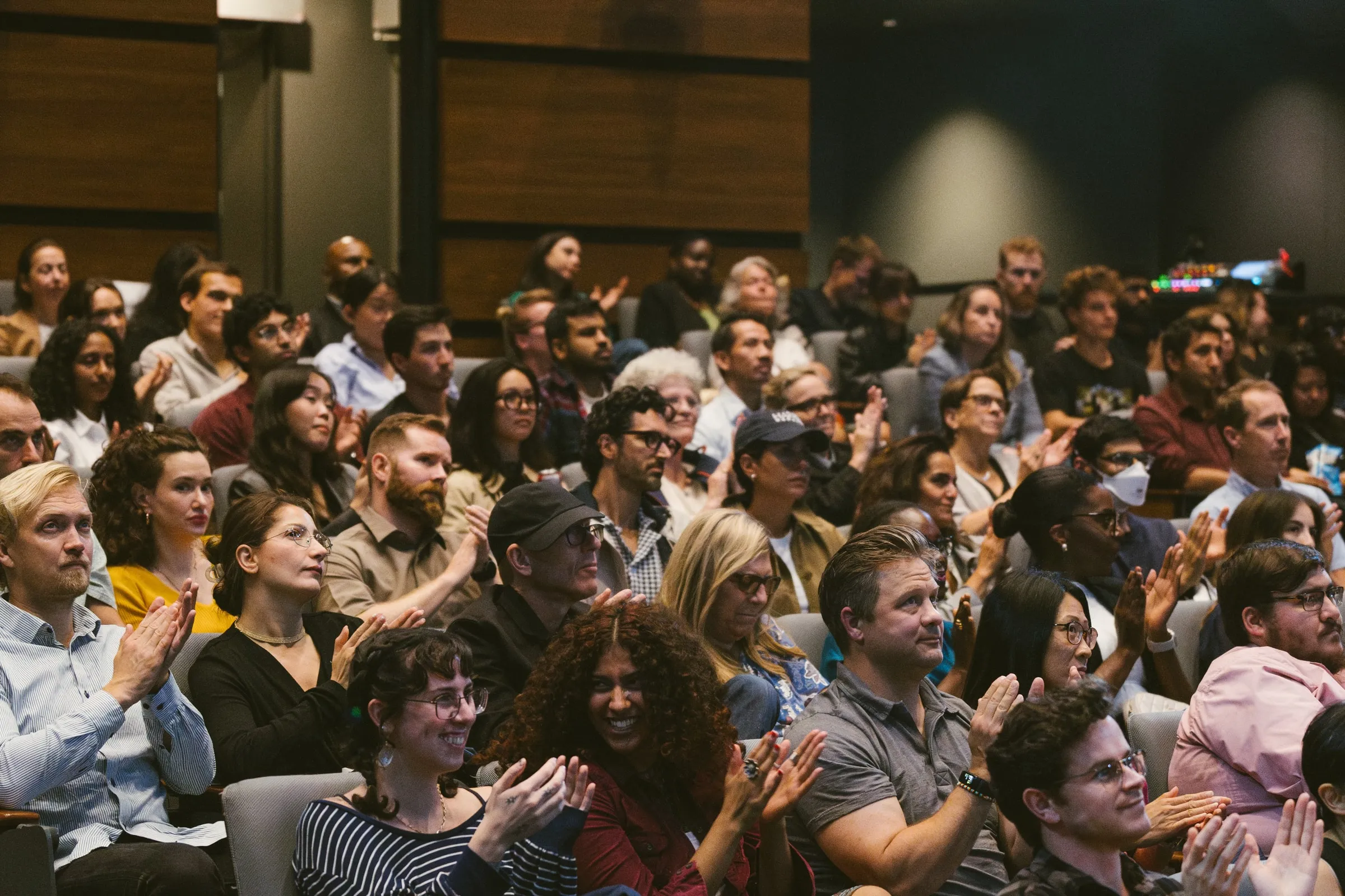 The audience applauds in the tiered Innis Town Hall auditorium.